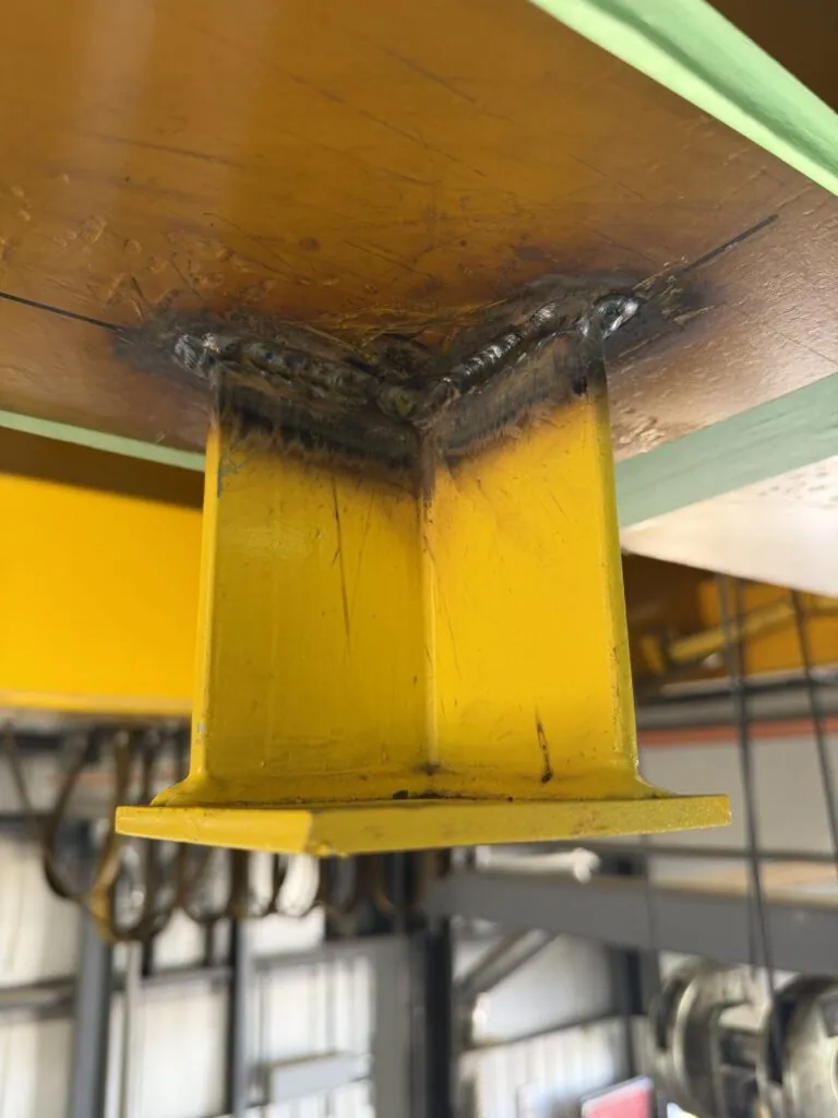 Close view of a CSA W59 weld joining a stand-off drop to the underside of the crane girder.