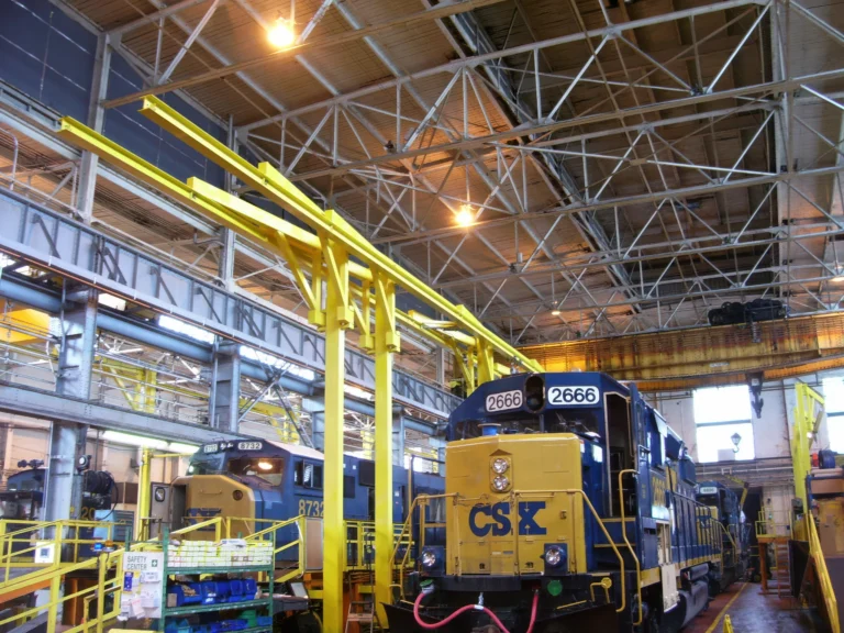 Yellow overhead rigid rail above locomotives in a service shop