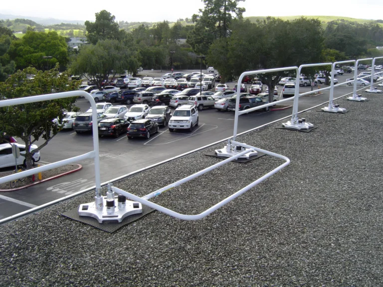White freestanding guardrail on weighted bases along a gravel roof edge