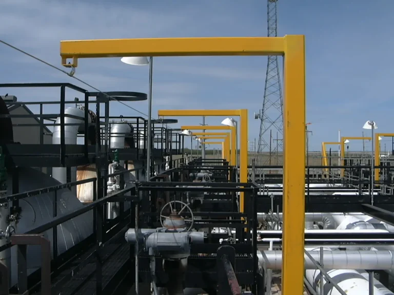 Yellow overhead rigid rail frames over a process piping deck