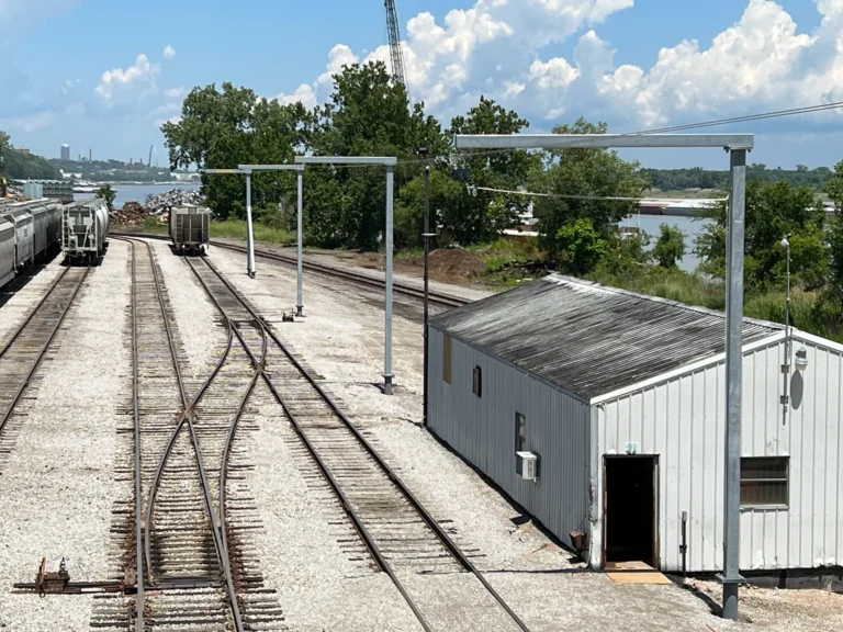 Galvanized overhead rail posts along railcar tracks beside a river