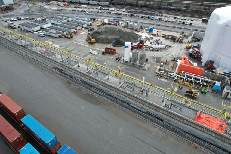 Aerial view of a rail yard with platform sections and guardrail being installed along the track