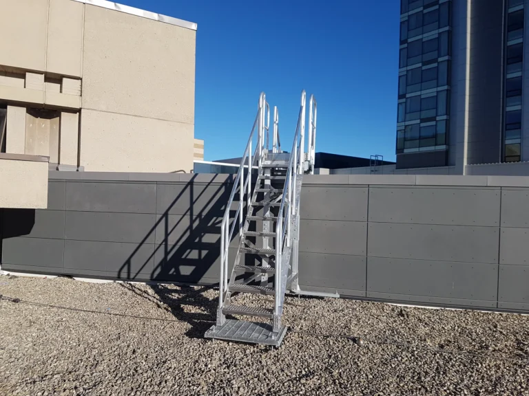 Aluminum stairs with handrails leading down to a lower rooftop level