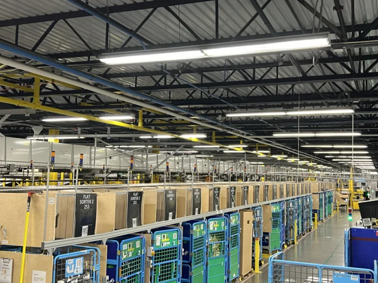 Yellow overhead rigid rail above a parcel sortation line in a distribution facility