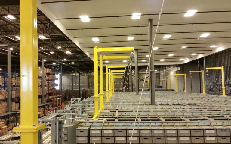 Yellow overhead rigid rail frames above rows of storage in a warehouse